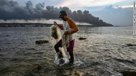 مردی هنگام برخاستن دود از آتش سوزی گسترده در یک انبار سوخت در ماتانزاس، کوبا، در 9 اوت 2022 ماهی می گیرد.