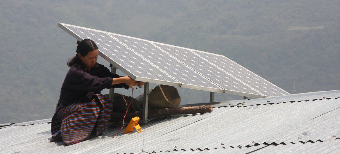 یک زن یک پنل خورشیدی را روی سقفی در بوتان نصب می کند.